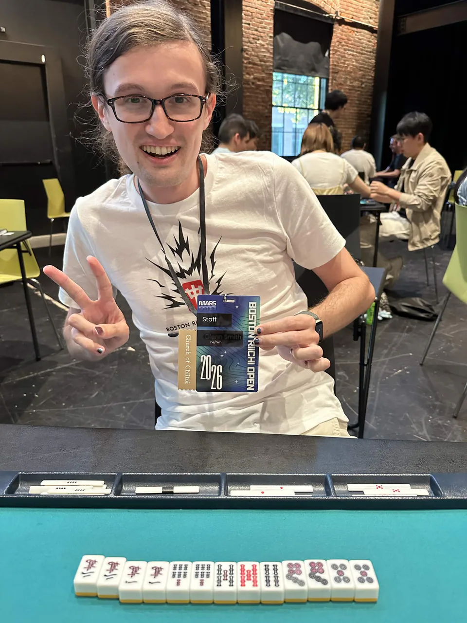 A seven-pairs chiitoitsu hand displayed in front of a smiling staff member at the first Boston Riichi Open